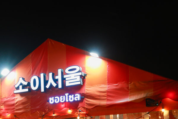 หน้าร้านซอยโซล สาขาช้างคลาน มองมุมเฉียง เต็นท์ส้มกับป้ายไฟ 소이서울 · ซอยโซล ตอนกลางคืน